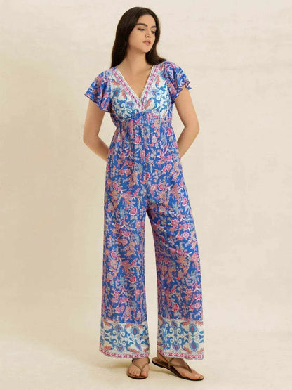 Woman wearing a blue and pink printed V-neck wide leg jumpsuit with buttoned and ruched details